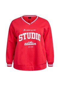 Červená mikina s výstrihom do V a dlhými rukávmi. Obsahuje biele písmo s nápisom "STUDIO edition" a pruhované manžety na zápästiach.