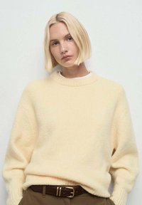 Suéter de punto amarillo claro con cuello redondo y mangas largas. Confeccionado en material suave, presenta un corte relajado y detalles acanalados.