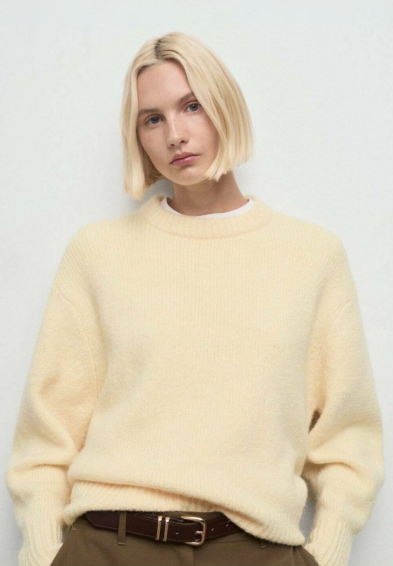 Suéter de punto amarillo claro con cuello redondo y mangas largas. Confeccionado en material suave, presenta un corte relajado y detalles acanalados.