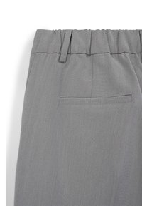 Pantalons en tissu gris avec une taille élastique, présentant une texture lisse et une poche arrière unique avec un détail de couture plate.