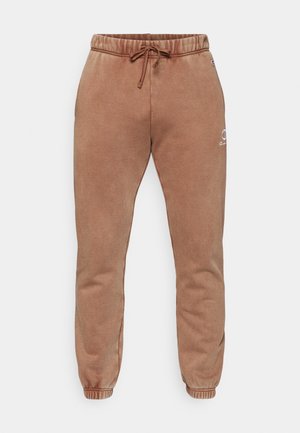 Hnedé tepláky vyrobené z mäkkého materiálu s elastickým pásom, šnúrkou na sťahovanie a zúženými manžetami. Na prednej strane sa nachádza malé logo.