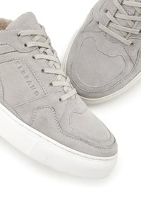Hellgraue Wildleder-Sneaker mit Schnürdesign, strukturiertem Gummisohle, gepolstertem Schaft und subtiler Markenkennzeichnung an der Seite.