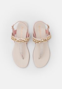 Beiga platta sandaler med en metallisk guld- och rhinestones utsmyckning på remmen, med en enkel tångdesign och justerbar bakrem.