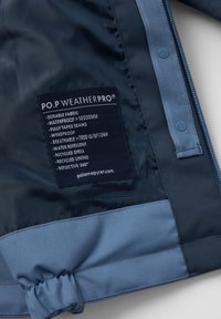 Merijärven sininen vedenpitävä takki, joka on valmistettu kestävästä kankaasta. Täydellisesti teipatut saumat, ja takissa on etiketti, jossa on hoito-ohjeet ja tiedot.