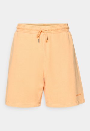 Breskvaste barve bombažne kratke hlače z elastičnim pasom in vrvico. Imajo ravno polico in detajl z logotipom na spodnjem levem delu.