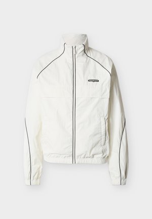 Λευκό ελαφρύ μπουφάν με ψηλό γιακά, μαύρο διακοσμητικό κατά μήκος των ραφών και μπροστι νό φερμουάρ. Διαθέτει λογότυπο στο πάνω αριστερό μέρος.