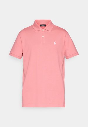 Roza bombažna polo majica s ovratnikom, kratkimi rokavi in dvema gumboma. Ima beli vezeni logotip na levi oprsju. Gladka tekstura.