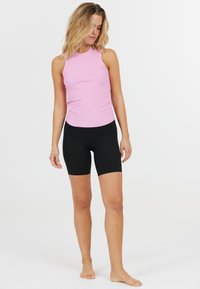 Lyserød ærmeløs top med ribbet tekstur, parret med sorte tætsiddende cykelshorts. Sættet har et enkelt, strømlinet design.