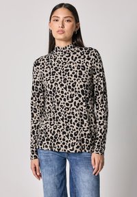 Hnědá a černá halenka s leopardím potiskem, dlouhý rukáv, vysoký límec a měkká textilie, spárována s světle modrými džíny.