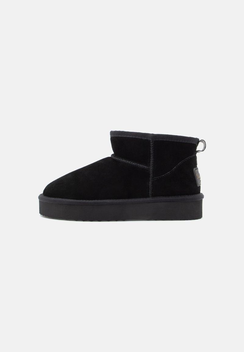 Botas de tobillo de ante negro con puntera redondeada, un forro suave y una lengüeta en el talón. Suela de goma negra gruesa y texturizada.
