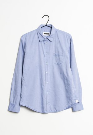 Jasnoniebieska koszula na długi rękaw z kołnierzykiem i kieszenią na piersi, zawieszona na czarnym wieszaku na białym tle.