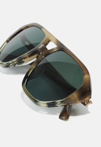 Ochelari de soare tortoise brown și tan cu lentile verzi, cu ramă pătrată supradimensionată și accente din metal pe tâmple.
