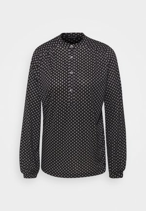 Schwarzes Langarmshirt mit einem weißen Diamantmuster, einem Stehkragen und einer Knopfleiste vorne. Glatte Stofftextur.