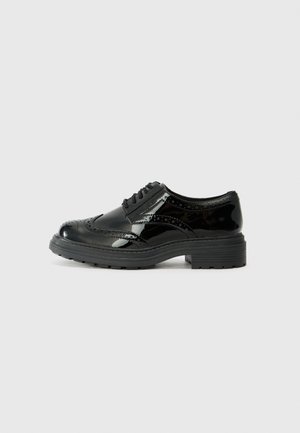 Chaussures oxford en cuir verni noir avec des détails texturés, bout rond, design à lacets et semelle épaisse en caoutchouc noir.