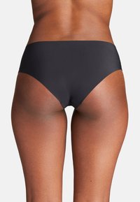 Černé bikiny s hladkým, elastickým materiálem, s nízkým pasem a minimálním pokrytím. Bez viditelného kovového zapínání nebo vzorů.