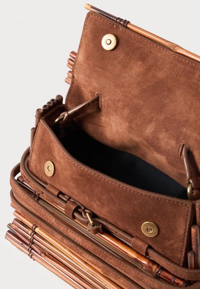 Καφέ τσάντα από σουέντ και μπαμπού, ανοιχτή, που δείχνει μαύρη εσωτερική επένδυση και χρυσό μαγνητικό κλείσιμο στο καπάκι.