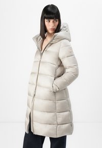 Gevoerde lange jas in lichtbeige, met een ritssluiting, capuchon en zijzakken. Gladde textuur met horizontale stiksels.