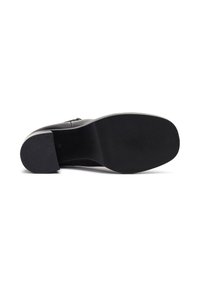 Zapato de tacón negro con parte superior de cuero liso, que presenta una suela de goma texturizada y una punta redondeada. Los acentos incluyen detalles de costura sutiles.