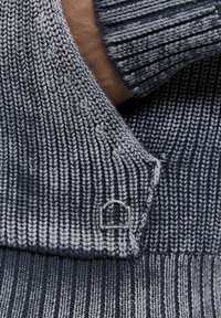 Maglione lavorato a maglia in blu scuro e grigio con texture a costine. Presenta un colletto ripiegato e un piccolo etichetta con logo sulla cucitura.