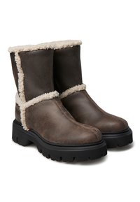 Stivali in pelle marrone con fodera morbida color crema, altezza alla caviglia e suola nera robusta. Dettagli di cucitura lungo le cuciture.