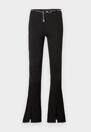 Black stretch pants with flared legs, featuring side slits and a chain belt accent. Smooth texture and tailored design for a fitted look.