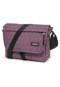 Bolso mensajero de tela morada con patrón de lazos, correa de hombro negra desmontable, tapa delantera y detalle de bolsillo con cremallera. Marca Eastpak visible.