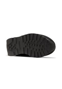 Schwarze Gummisohle mit strukturiertem Profilmuster, das erhabene kreisförmige Griffe und geriffelte Kanten für Traktion und Stabilität aufweist.