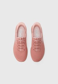 Pair of pink Skechers slip-on sneakers with knit texture and elastic laces, viewed from above on a plain white background.