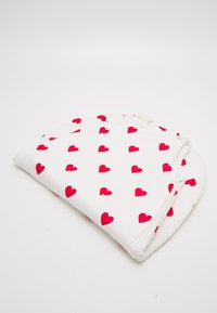 White fabric blanket featuring a repeated pattern of small red hearts. Soft texture with rounded edges and tied corners for secure use.