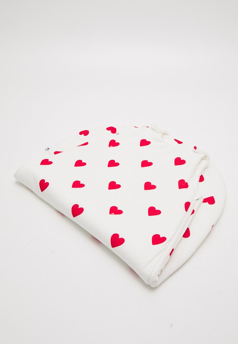 White fabric blanket featuring a repeated pattern of small red hearts. Soft texture with rounded edges and tied corners for secure use.