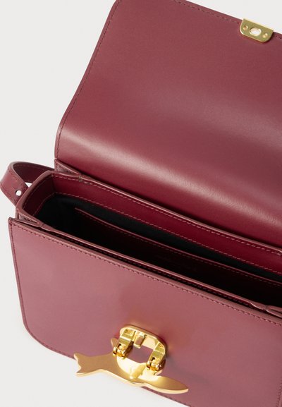 Μικρή τσάντα χειρός από δέρμα μπορντό με ανοιχτό καπάκι, που διαθέτει χρυσό μεταλλικό κούμπωμα σε σχήμα πουλιού σε πτήση και εσωτερική τσέπη.