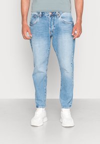 Jasnoniebieskie dżinsy z denimu o prostych nogawkach, z pięcioma kieszeniami i subtelnym przetarciem. Wykończone zapięciem na guziki oraz kontrastującymi szwami.