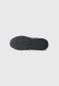 Black sneaker sole with textured tread pattern, featuring deep grooves and an embossed logo, designed for traction and durability.