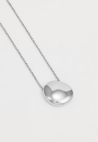Colier cu pandantiv din argint, având un charm oval, lustruit, pe un lanț, cu branding gravat. Textură netedă, design minimalist.