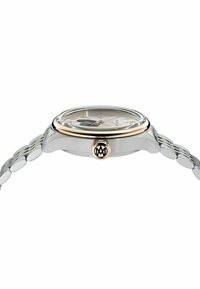 Reloj analógico en tonos plateado y dorado con esfera redonda, dial transparente y pulsera de eslabones metálicos. Presenta un logotipo en la corona y un diseño minimalista.
