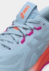 Zapatilla de running ASICS azul claro con logo naranja en la lengüeta, ojales rosas, parte superior de malla transpirable y detalle naranja en la entresuela.