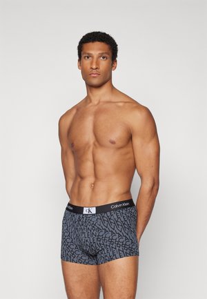 Bóxers de Calvin Klein con un estampado en negro y gris que incluye texto del logo, cintura elástica cómoda y diseño ajustado.