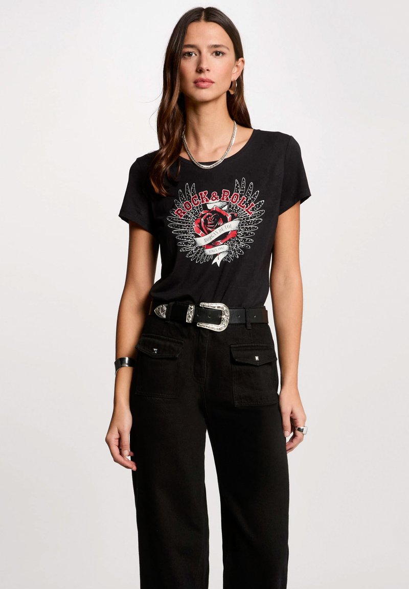 T-shirt nera in cotone con una grafica "Rock & Roll" caratterizzata da un design con rosa e ali. Abbinato a pantaloni neri a vita alta e una cintura larga.