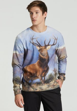 Langærmet sweatshirt med et realistisk hjorteprint på en blå landskabsbaggrund. Blødt stof med ribbede manchetter og kant.