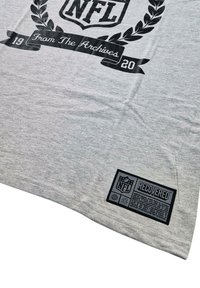 Gray T-shirt featuring a black NFL logo and text "From The Archives" with laurels. Embroidered label at the bottom reads "RECOVERED."