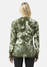 Grüner Batik-Kabelstrickpullover mit gerippten Bündchen und fransigem Saum. Zeigt ein strukturiertes Muster und weichen Stoff von der Rückansicht.