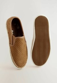 Chaussures brown à enfiler avec une texture tissée, semelle en caoutchouc blanc et motif chevron au bas. Les accents incluent des détails de couture.