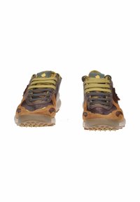 Sneaker marroni e beige con una parte superiore in suede testurizzato, lacci verdi e gialli, e una suola sagomata con piccole punte per la trazione.