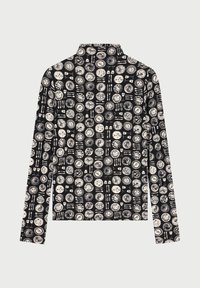Zwart shirt met lange mouwen en een terugkerend patroon van witte cirkelvormige ontwerpen, met diverse grafische elementen en texturen. Hoog kraagontwerp.