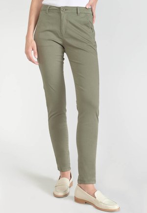 Pantalons slim fit vert olive en coton, dotés d'une fermeture éclair, de poches avant et d'une texture lisse, associés à des mocassins beiges.