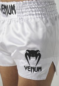 White satin shorts featuring a black embroidered logo of a spider and the word "VENUM," with side slits for added mobility.