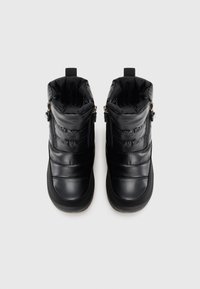 Une paire de bottes d'hiver noires isolées avec des fermetures éclair sur le côté et des tirants, conçues pour la chaleur et la facilité d'enfilage.