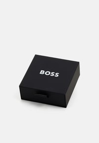 Black rectangular gift box with a matte finish, featuring a silver "BOSS" logo on the top and a pull tab for opening.