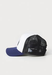 Kasket med hvid front, blåt skygge og sort netbag. Har et struktureret design og broderet logo på siden. Teksturede overflader.