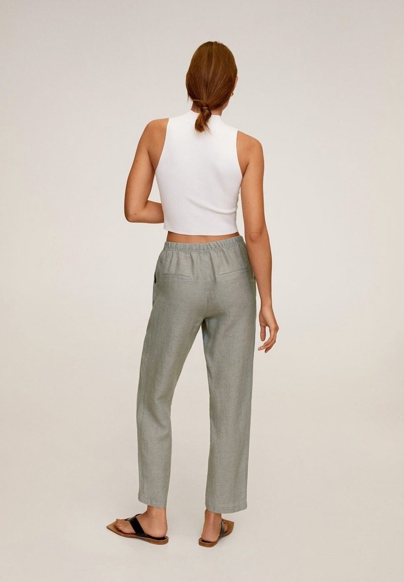 Pantalons en mélange de lin gris clair, à coupe décontractée, avec taille élastique et deux poches arrière, associés à un top sans manches en côtes blanches.